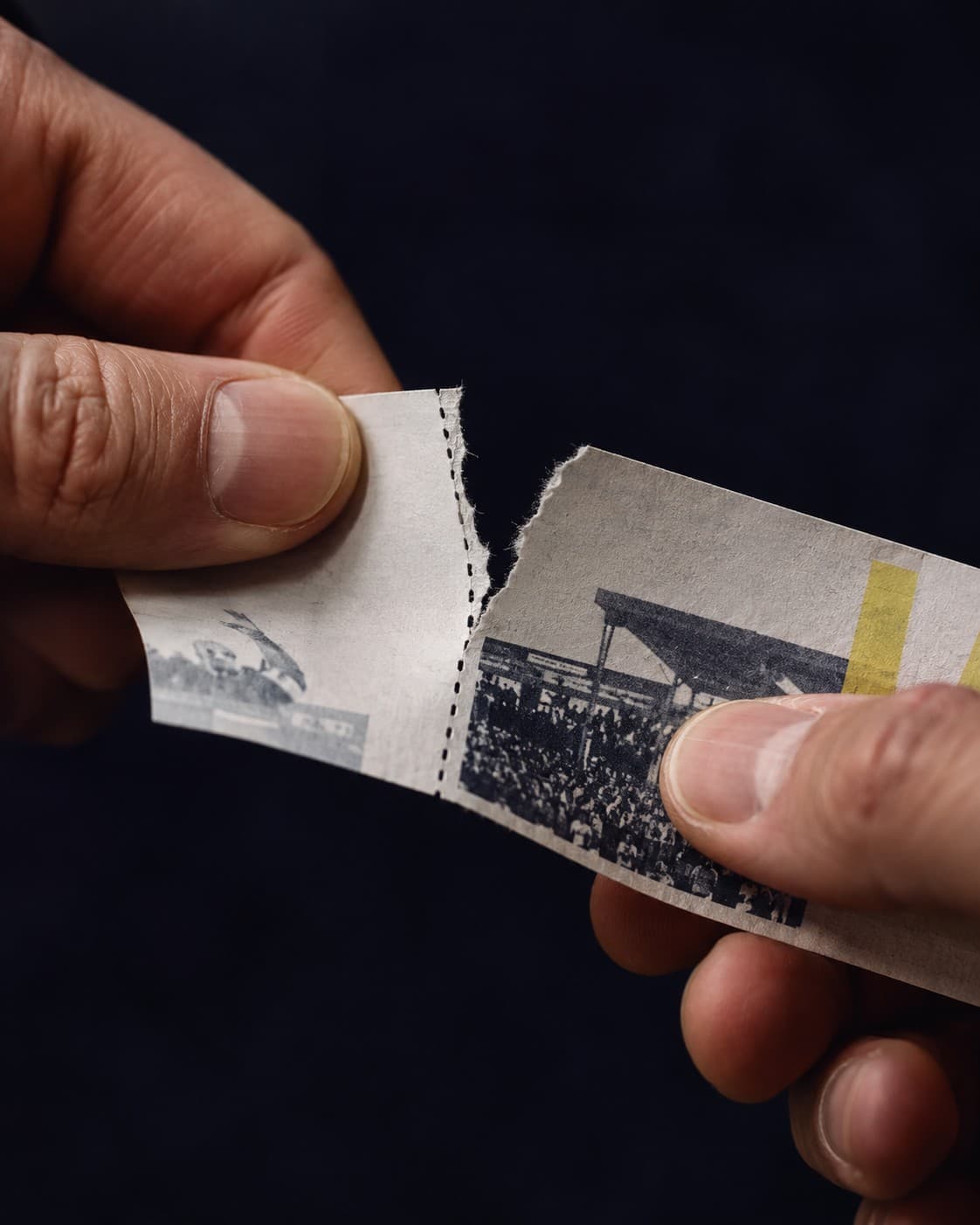 Two hands tearing a printed ticket along its perforation